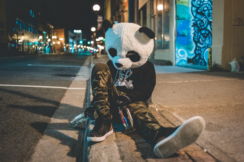 man with panda head sitting on the ground