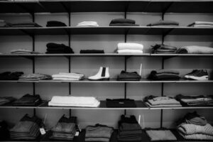 grayscale photography of assorted apparels on shelf rack