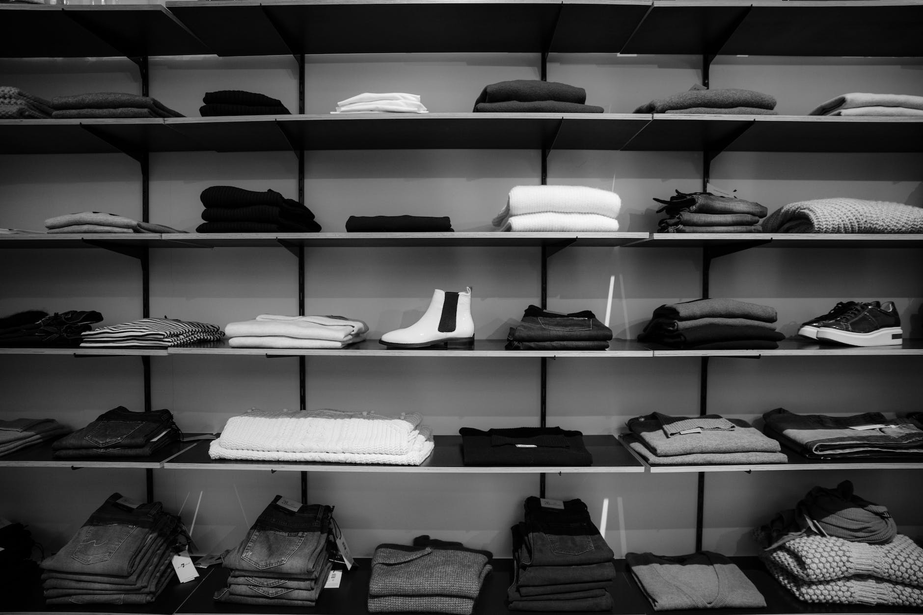 grayscale photography of assorted apparels on shelf rack