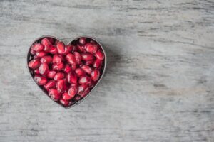 silver heart bowl filled of red pomegranate seeds