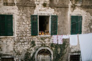 old shabby brick building with windows with opened shutters