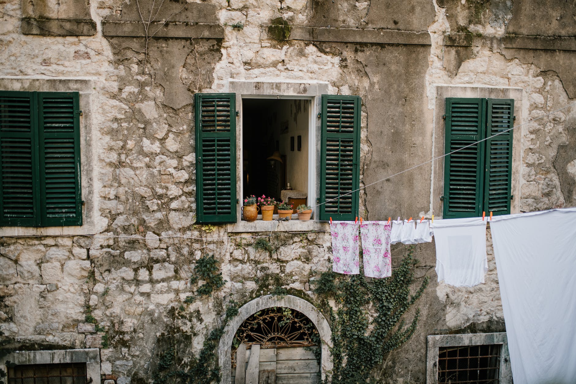 old shabby brick building with windows with opened shutters