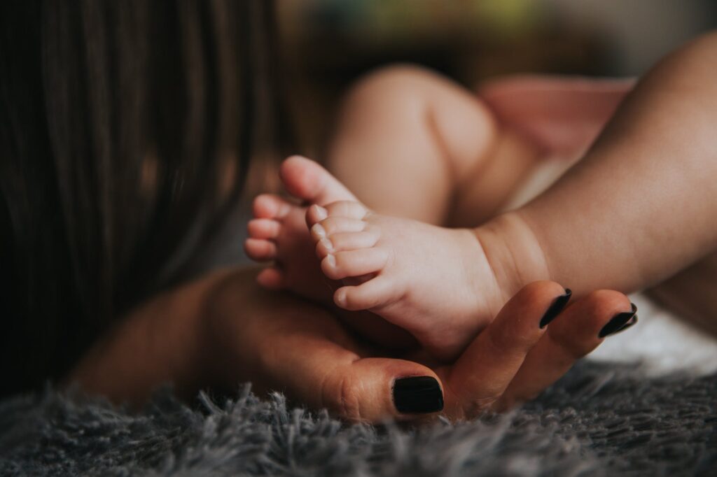 person holding baby s feet in selective focus photography
