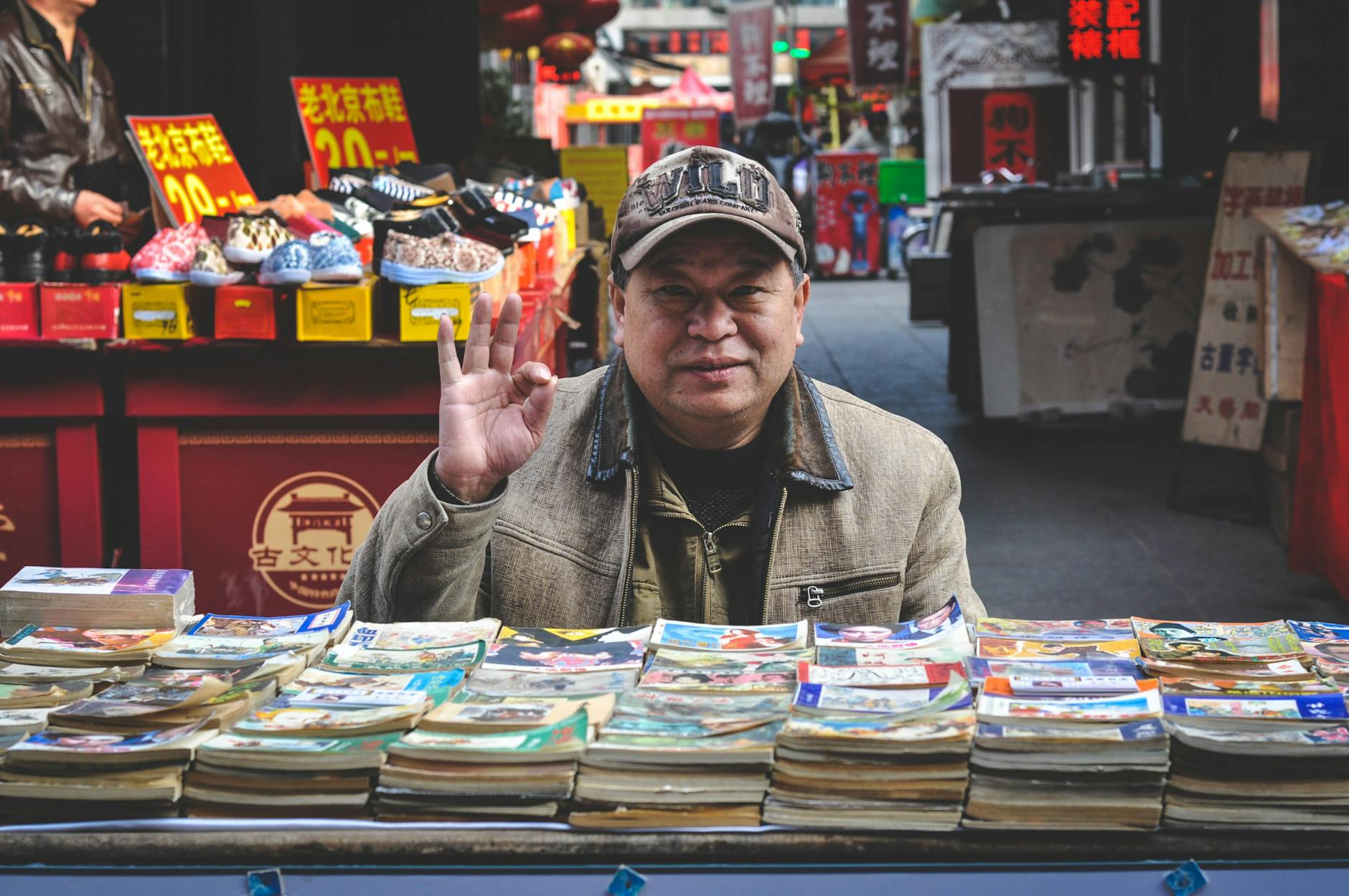 man in brown coat in front of books