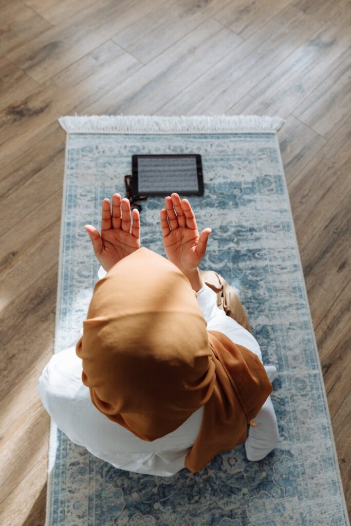 high angle shot of a person kneeling on a blue prayer rug
