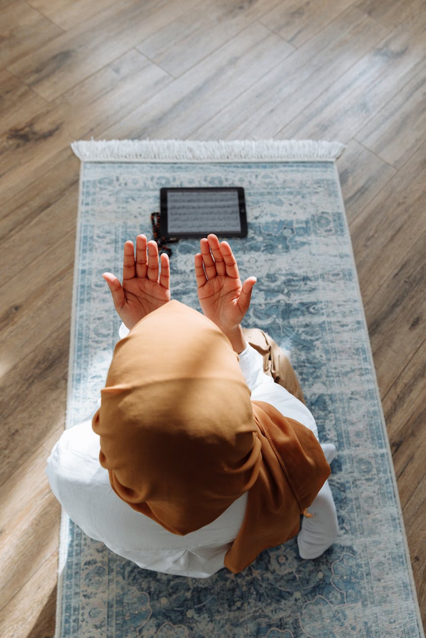 high angle shot of a person kneeling on a blue prayer rug